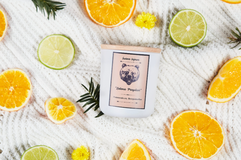 swieca-sojowa-zielona-przystan-pomarancza-bergamotka-naturalna-swieczka-z-drewnianym-wieczkiem-na-kocu-w-otoczeniu-plastrów-pomaranczy-i-limonki