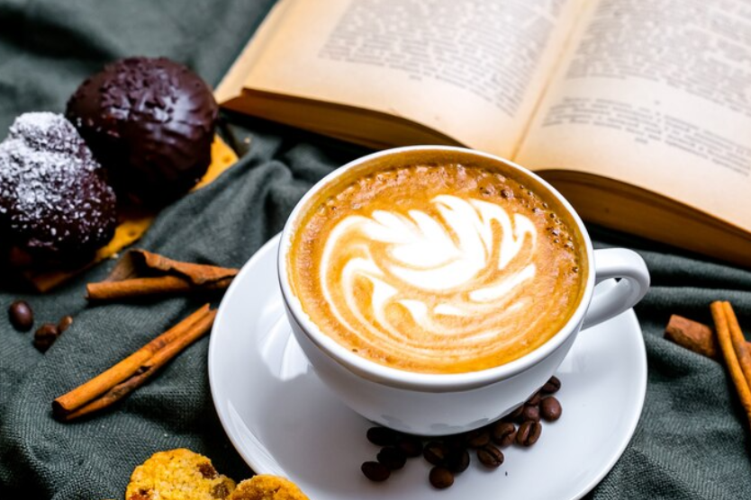 Cappuccino z latte art i książka w tle