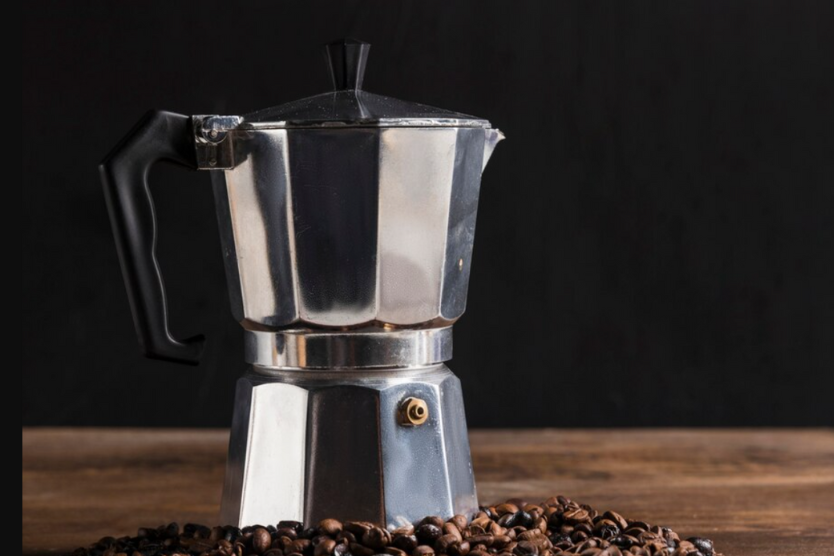 Kawiarka na tle czarnego tła z ziarnami kawy