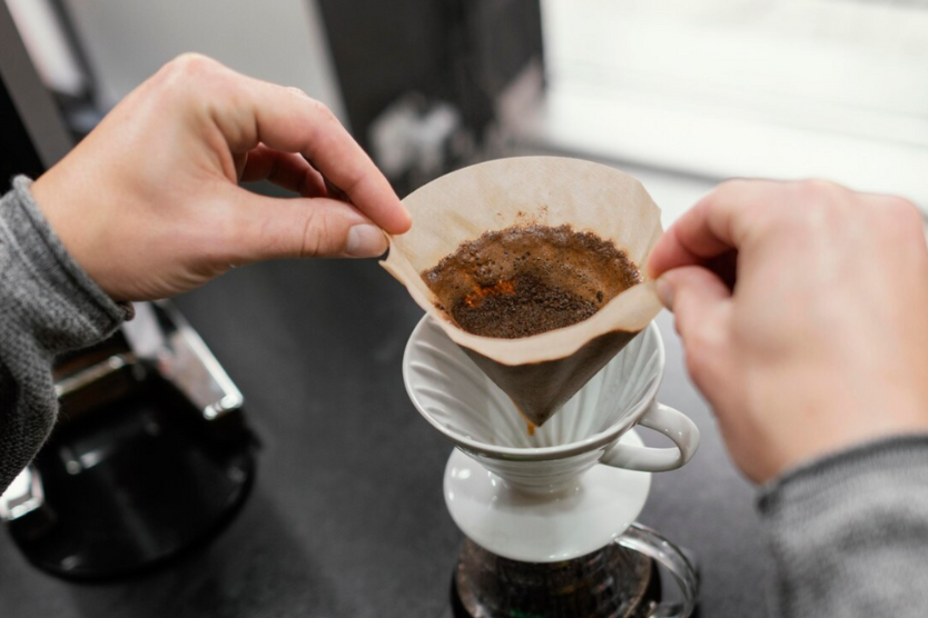 Ręce układające filtr z kawą w dripperze do parzenia kawy przelewowej.
