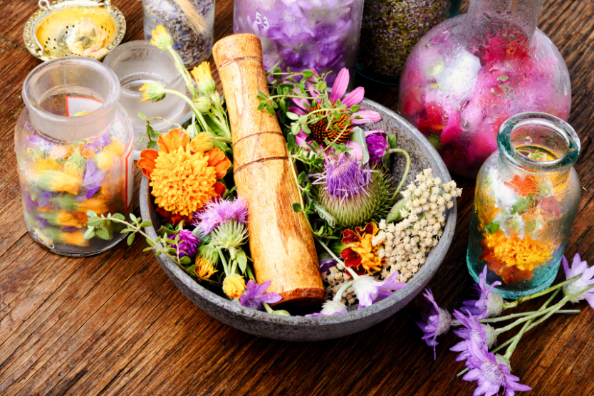  Kolorowe kwiaty i zioła w misce z moździerzem i buteleczkami z domowymi eliksirami